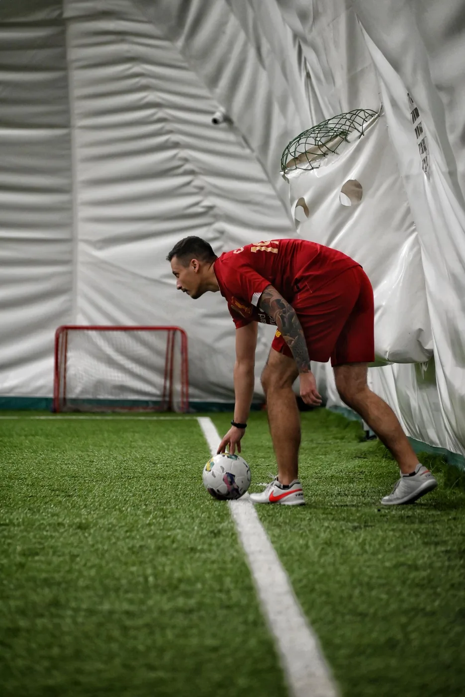 Football player preparing with a ball at a professional indoor training pitch